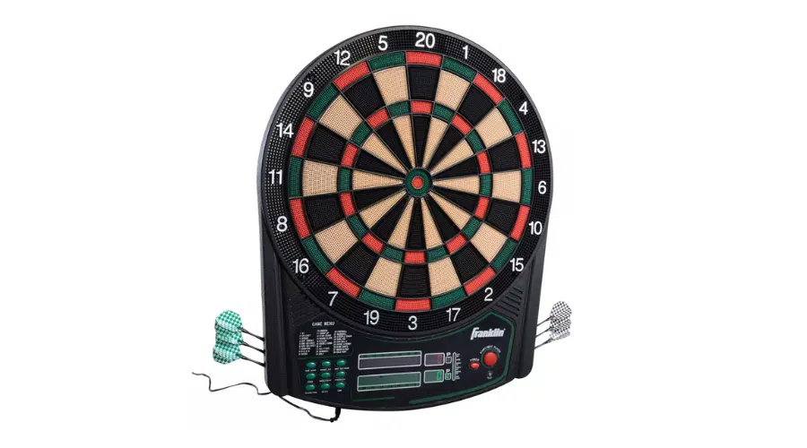 An electronic dartboard with a digital score display, several buttons, and three green-and-white darts placed at the side. The dartboard has multiple colored scoring sections and is plugged in with a visible power cord.