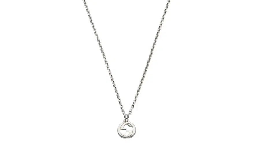 A silver chain necklace with a circular pendant featuring a cut-out geometric design in the center, displayed on a plain white background.